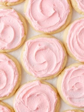 Overhead view of soft Crumbl sugar cookies topped with thick pink almond frosting.