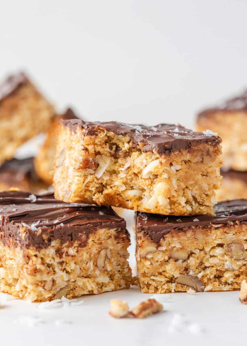 Close-up of a 5 star bar with coconut and pecans topped with a thick layer of melted chocolate and sea salt.