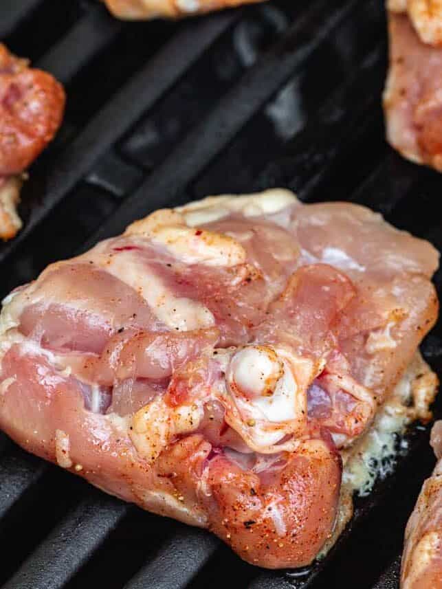 Chicken thighs skin down grilling over direct heat on the grill.