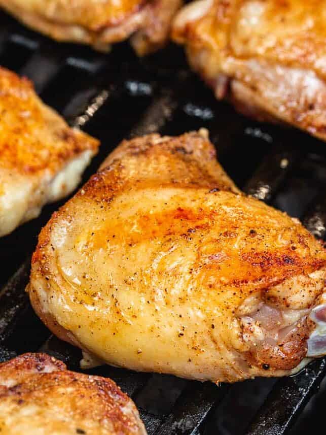 Chicken thighs skin side up on the grill.