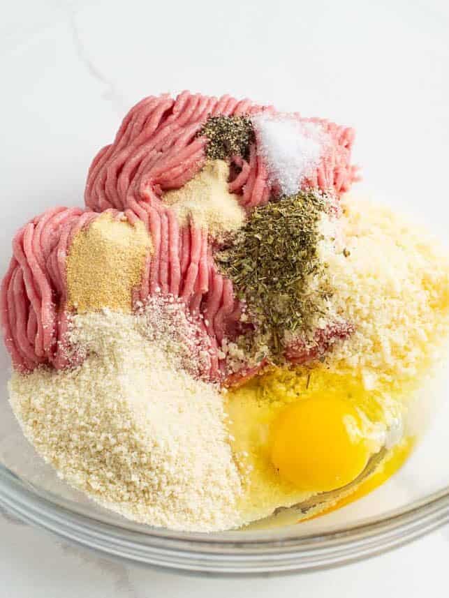 Ground chicken, egg, breadcrumbs, Parmesan and seasoning in a bowl.