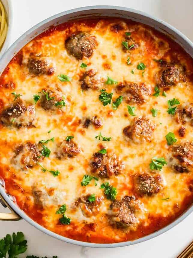Chicken parmesan meatballs simmered in marinara and covered with cheese in a skillet.