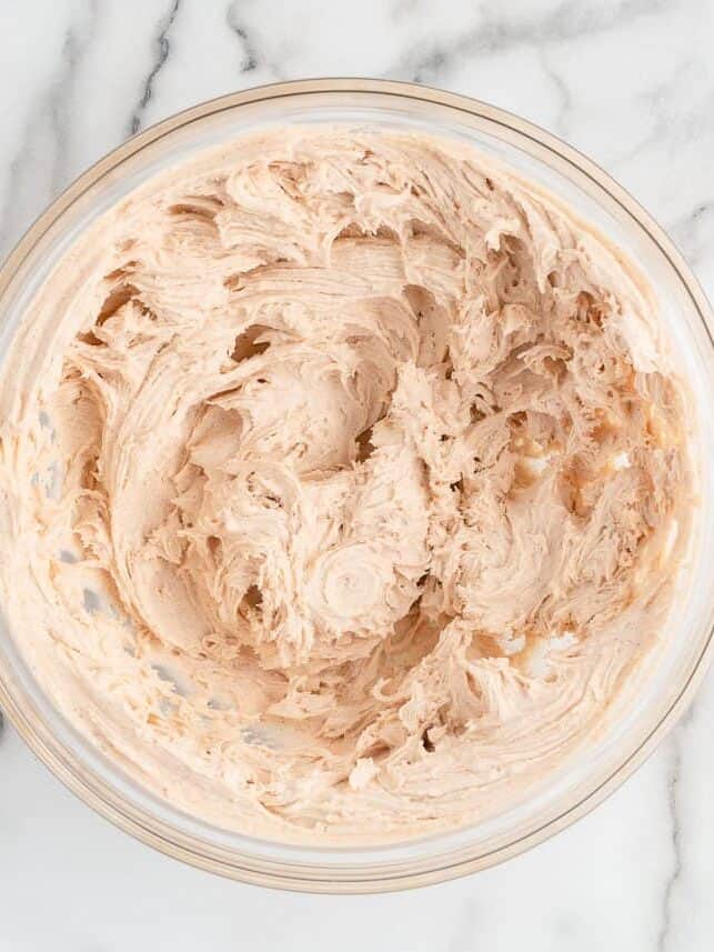 Cinnamon buttercream in bowl to top apple pie cupcakes.