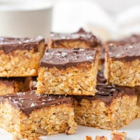 Stacked 5 star bars with a graham cracker, coconut and pecan base topped with chocolate.