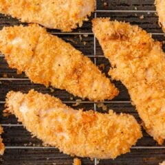 Close-up of golden crispy baked chicken tenders on a wire cooling rack.