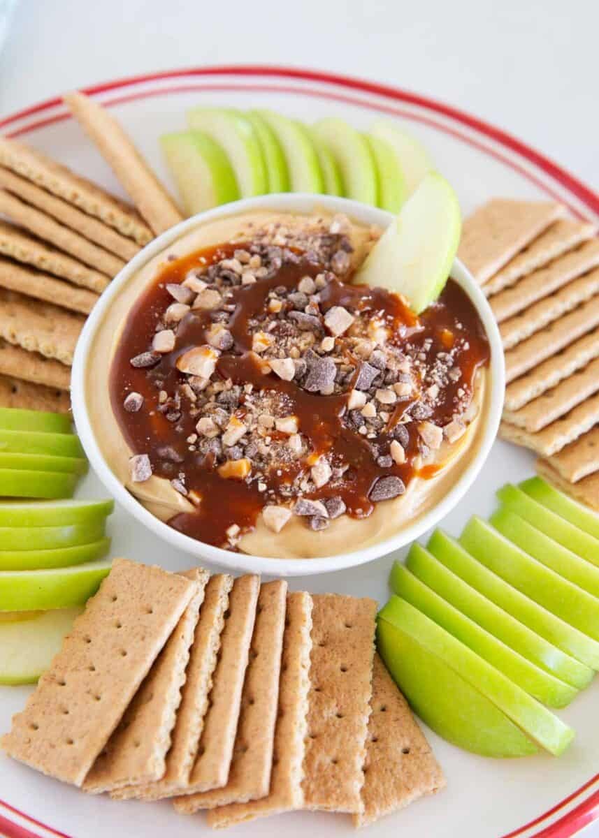 Close-up of creamy caramel apple cheesecake dip topped with caramel sauce and crunchy toffee bits.