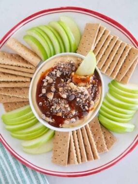 Overhead view of caramel apple cheesecake dip with sliced Granny Smith apples and graham crackers for dipping.
