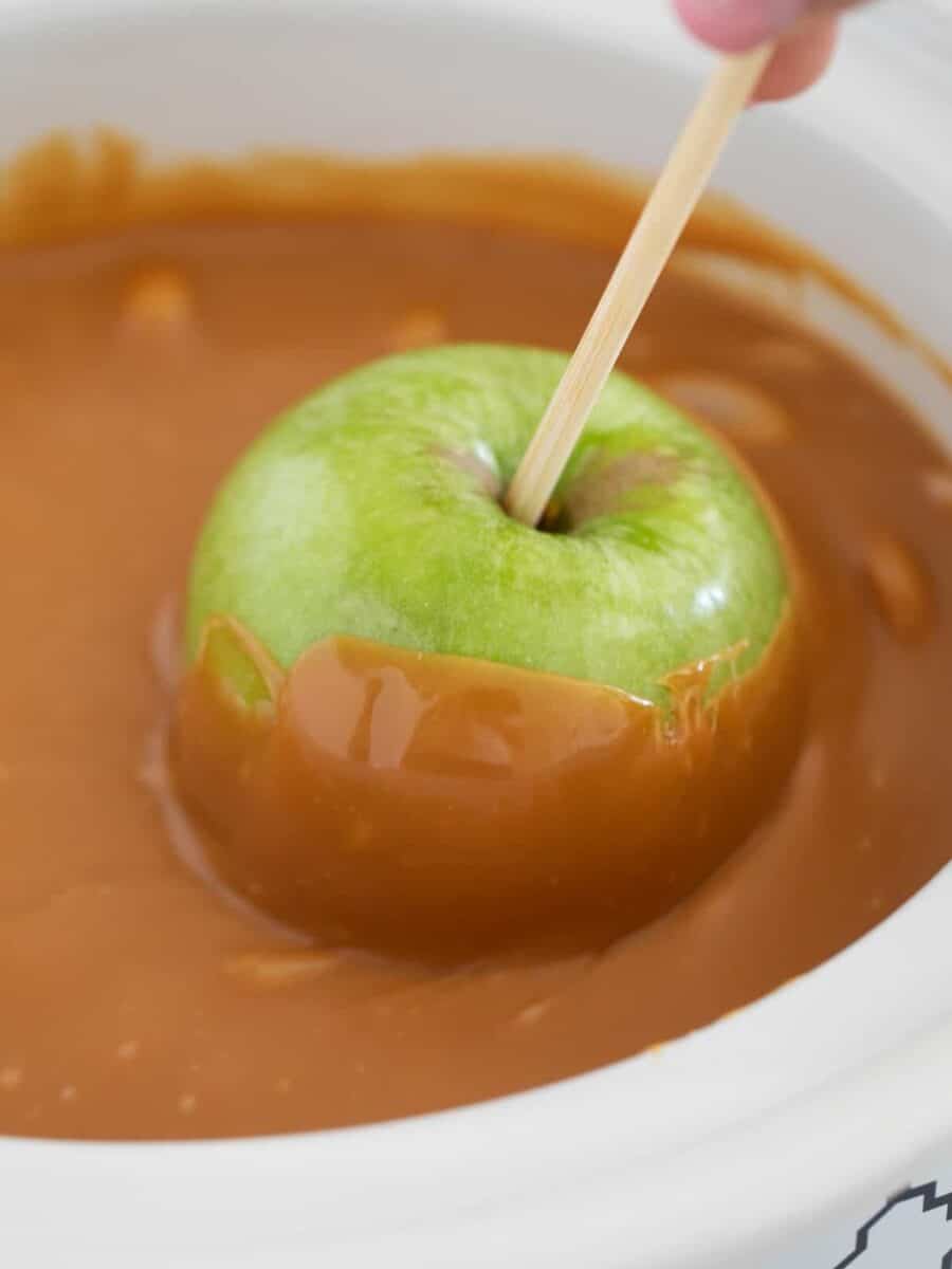Dipping apple into caramel.