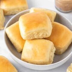 Soft and fluffy copycat Texas Roadhouse rolls brushed with melted butter and served in a bowl with cinnamon honey butter.