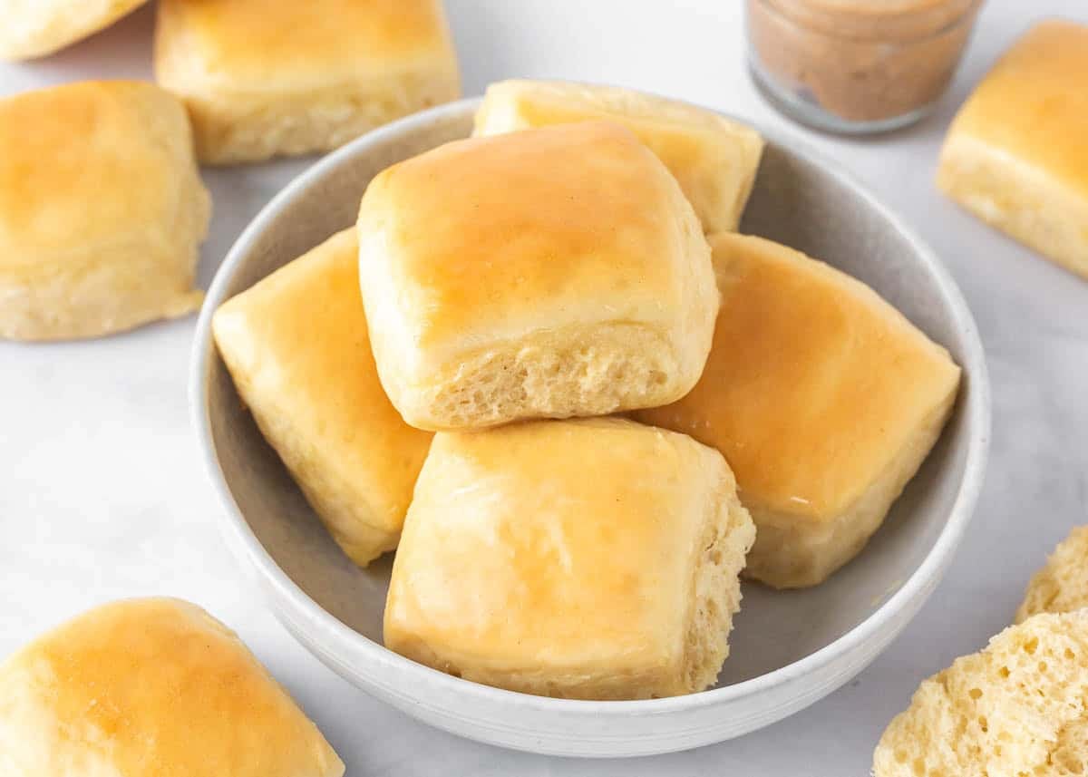 Soft and fluffy copycat Texas Roadhouse rolls brushed with melted butter and served in a bowl with cinnamon honey butter.
