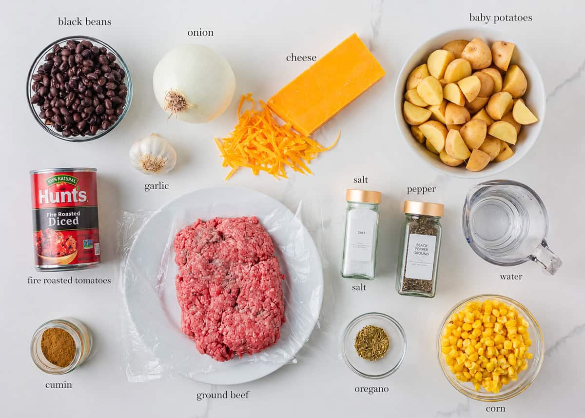 Ground beef, potatoes, corn, beans, cheese and seasonings on the counter for a crock pot cowboy casserole.