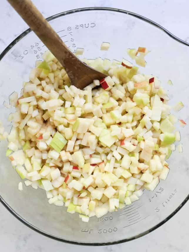 Finely diced apples in a glass measuring bowl for apple pie filling.