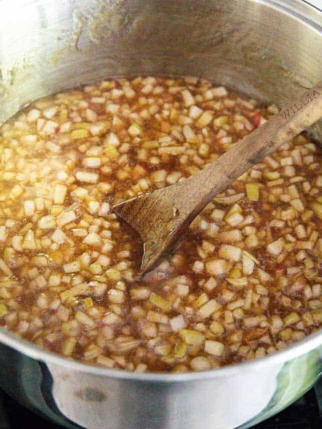 Diced apples simmering in a cinnamon-spiced sauce for homemade apple pie filling to layer in cheesecake.