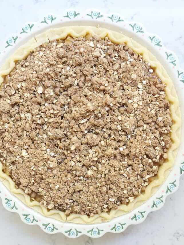 Unbaked apple pie cheesecake covered with a cinnamon oat streusel topping.