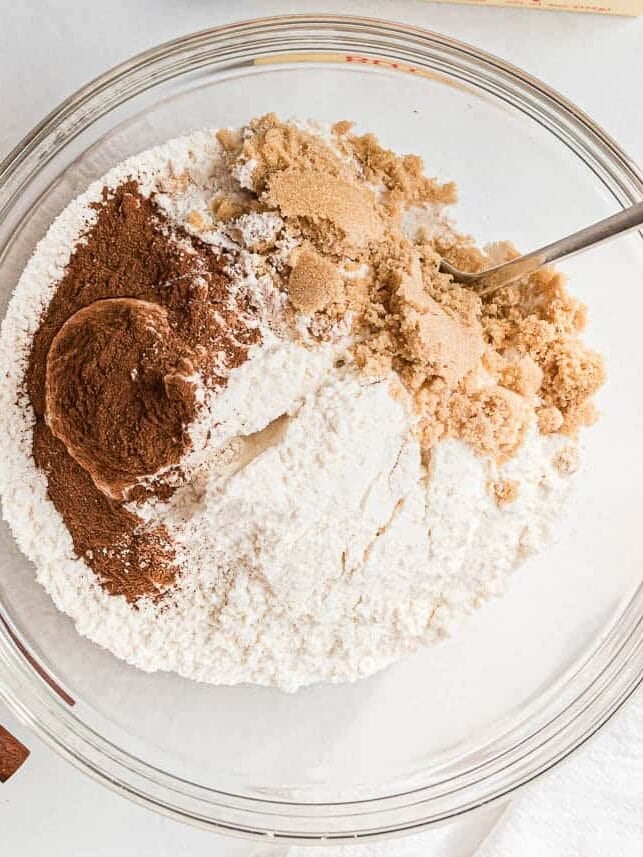 Yellow cake mix, brown sugar and cinnamon in a glass bowl before stirring together.