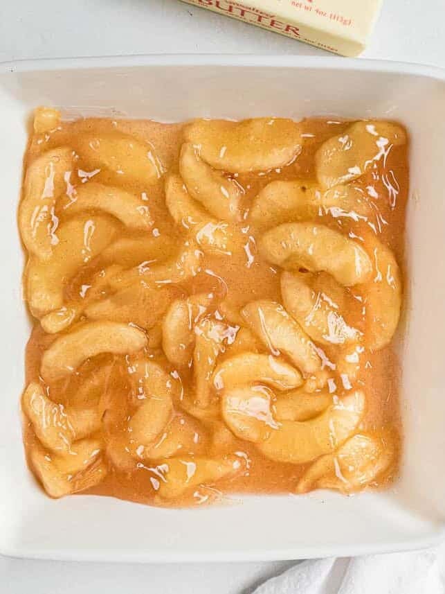 Canned apple pie filling spread in the bottom of a white 9x9-inch baking dish.