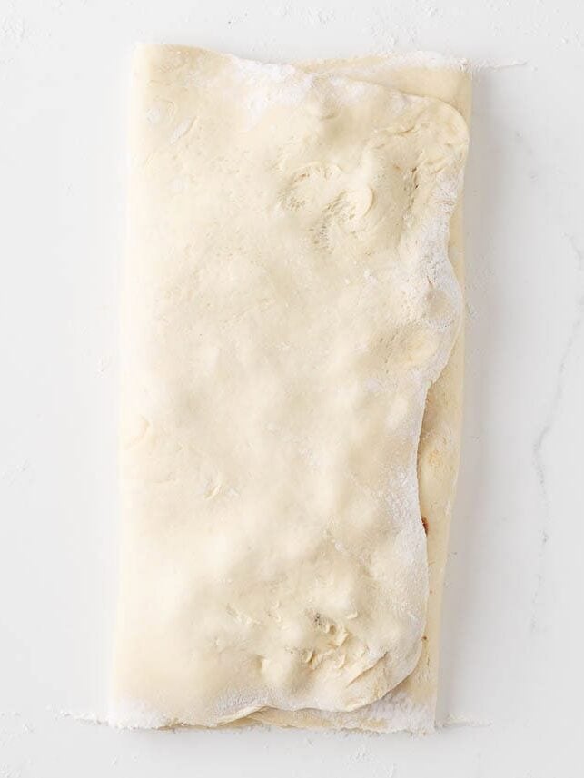Apple-filled yeast dough folded over before being cut and shaped into fritters.