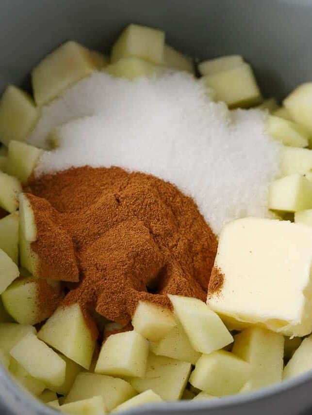 Diced apples with sugar, cinnamon and butter in a saucepan for apple fritter filling.