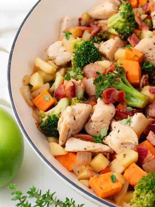 One pan chicken and apples with bacon, sweet potatoes and broccoli in a skillet.