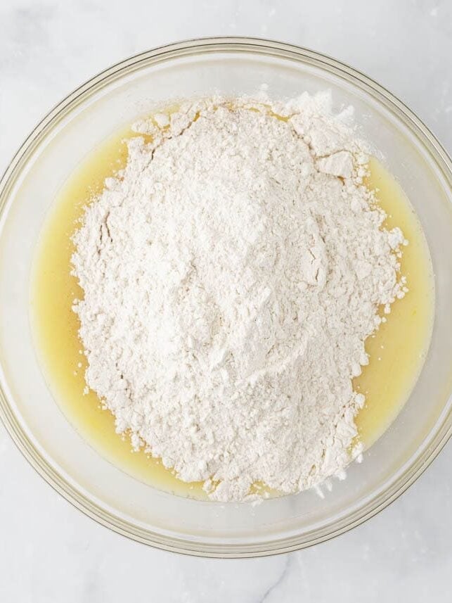 Showing wet ingredients combined in a bowl with flour, baking powder and baking soda ready to be folded into to make muffin batter.
