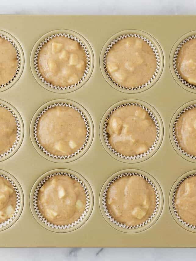Apple muffin batter divided evenly among 12 lined muffin cups.