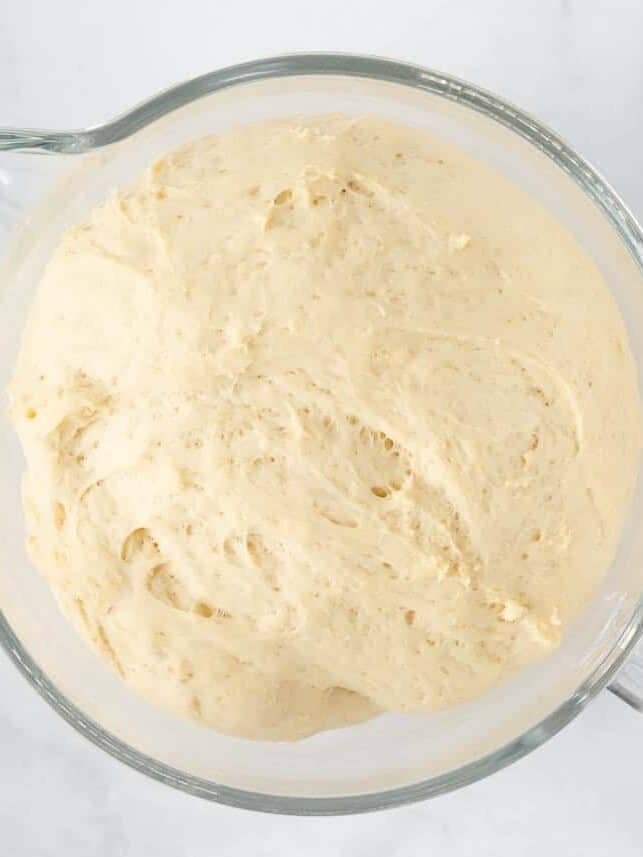 Risen yeast dough doubled in size in a glass mixing bowl