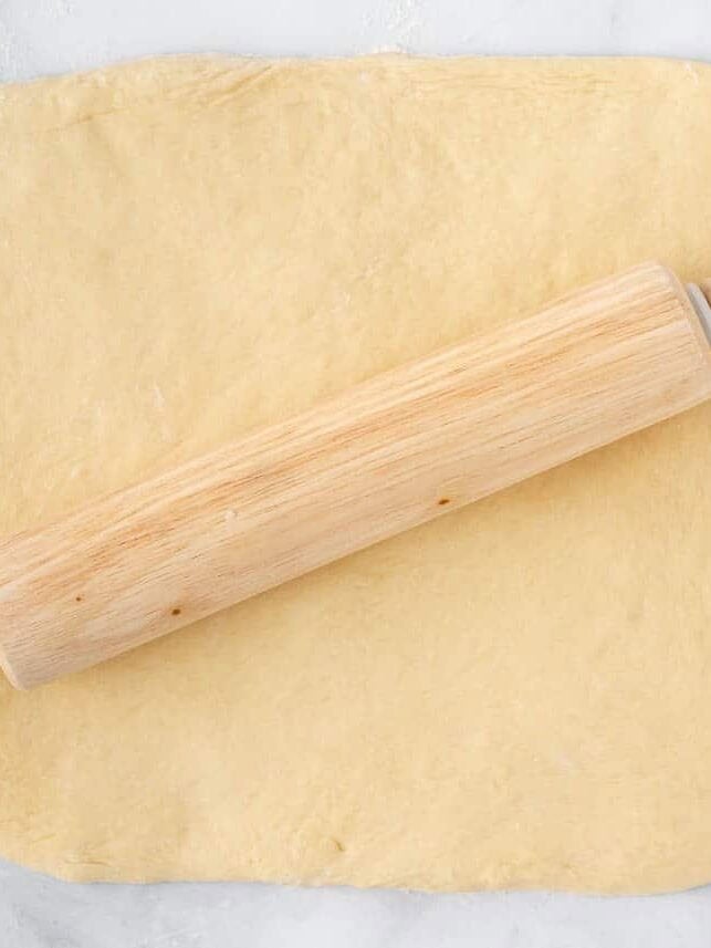 Texas Roadhouse roll dough rolled into a large rectangle with a rolling pin.