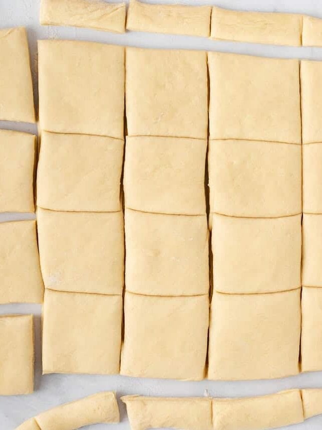 Rolled dough cut into evenly sized squares for Texas Roadhouse rolls.