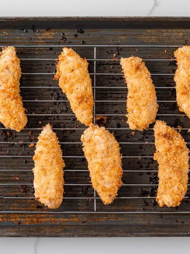 Crispy baked chicken tenders arranged on a wire rack over a baking sheet.