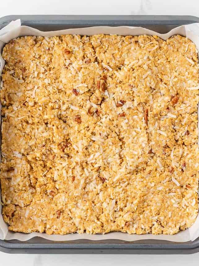 5 star bar mixture pressed evenly into a parchment-lined square baking pan before baking.