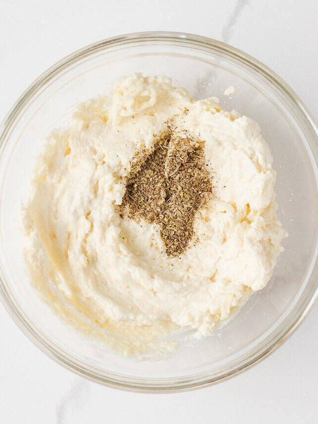 Ricotta cheese mixture with Italian herbs in a glass bowl for layering in easy lasagna casserole.