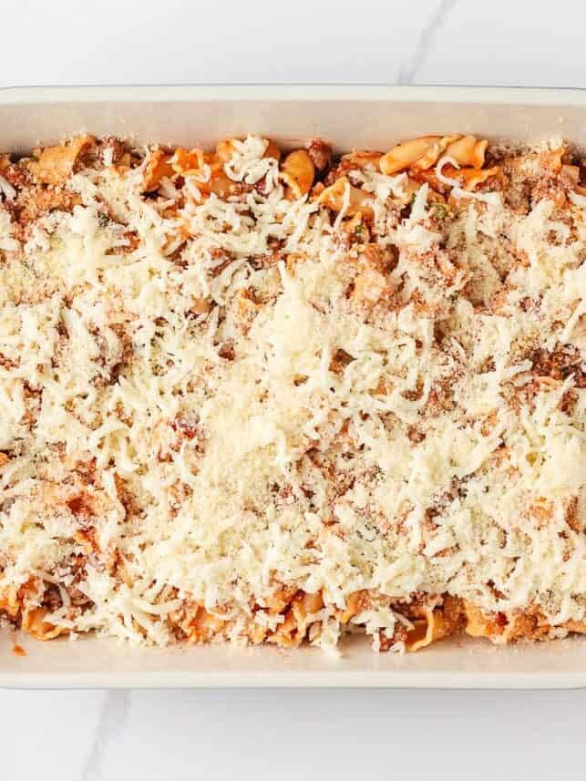 Unbaked lasagna casserole topped with shredded mozzarella and Parmesan cheese, ready to go in the oven.