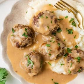 Overhead view of homemade meatballs with brown gravy and mashed potatoes.
