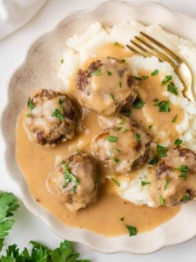 Overhead view of homemade meatballs with brown gravy and mashed potatoes.