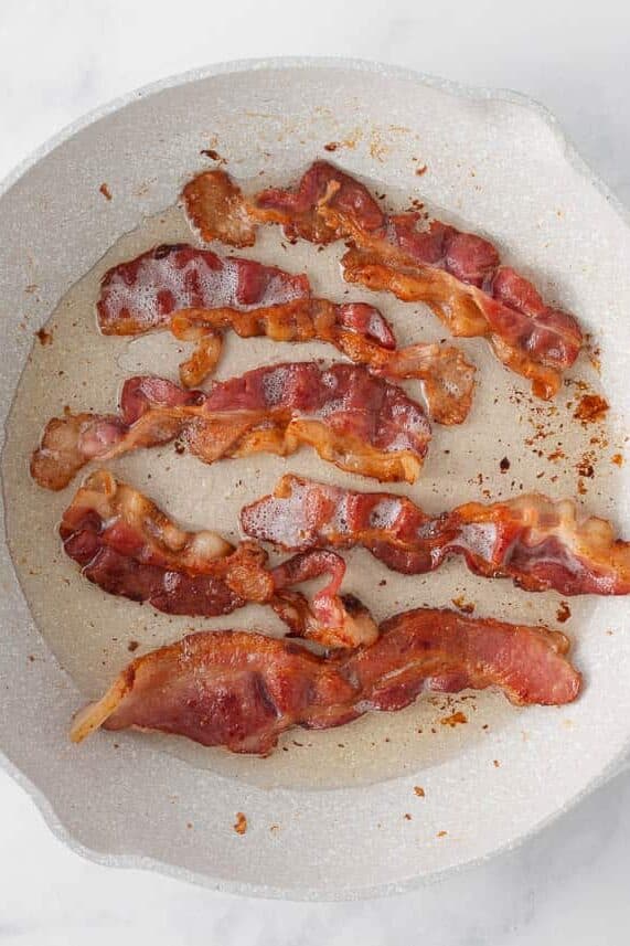 Bacon frying in a pan for loaded potato soup.