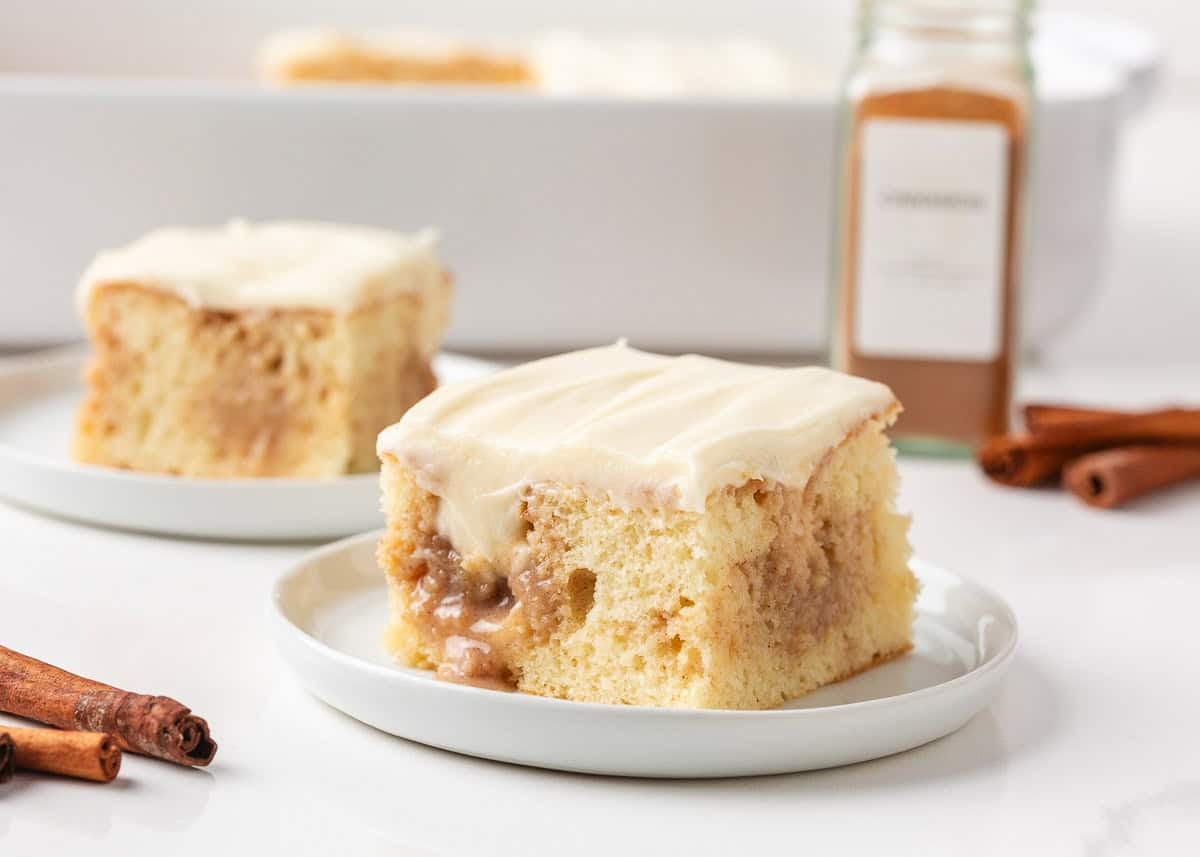 Cinnamon roll poke cake slices with cream cheese frosting and cinnamon filling.