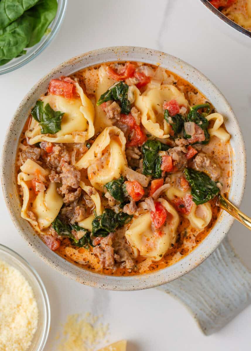 Bowl of creamy Tuscan tortellini soup with Italian sausage, spinach and diced tomatoes.