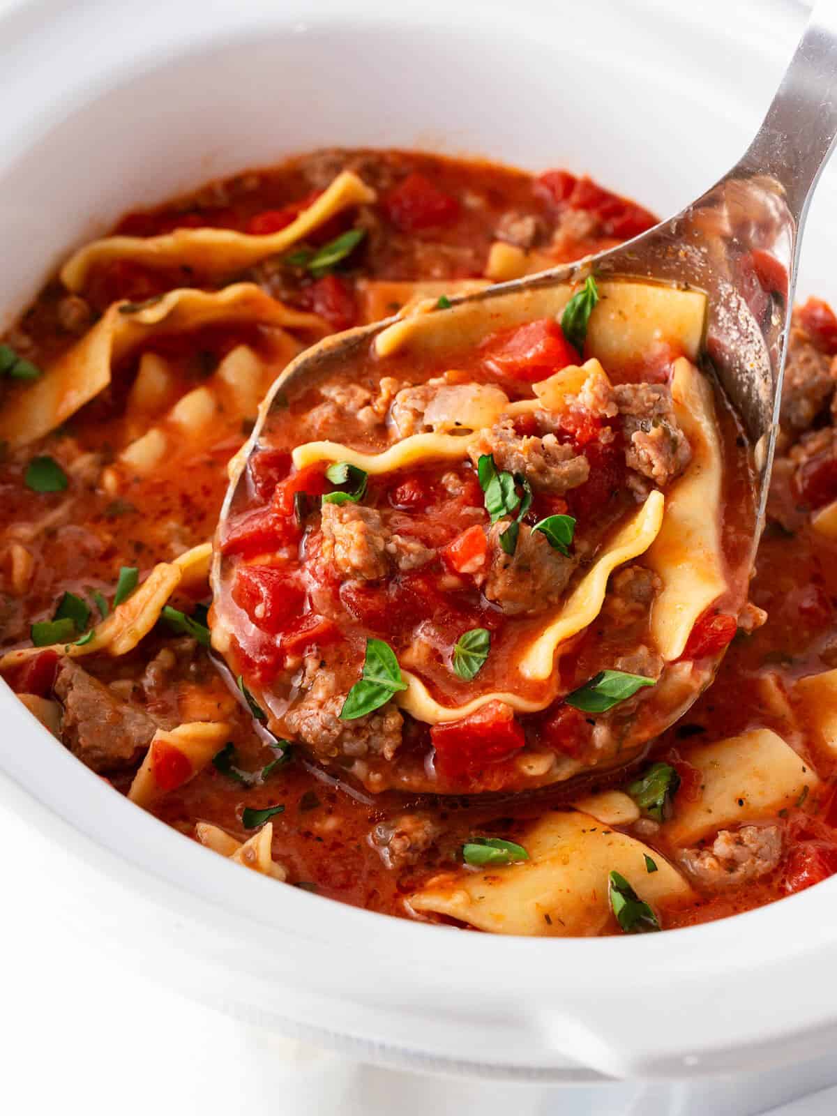 Crockpot lasagna soup with Italian sausage, tender lasagna noodles, tomatoes and fresh basil served from a slow cooker.