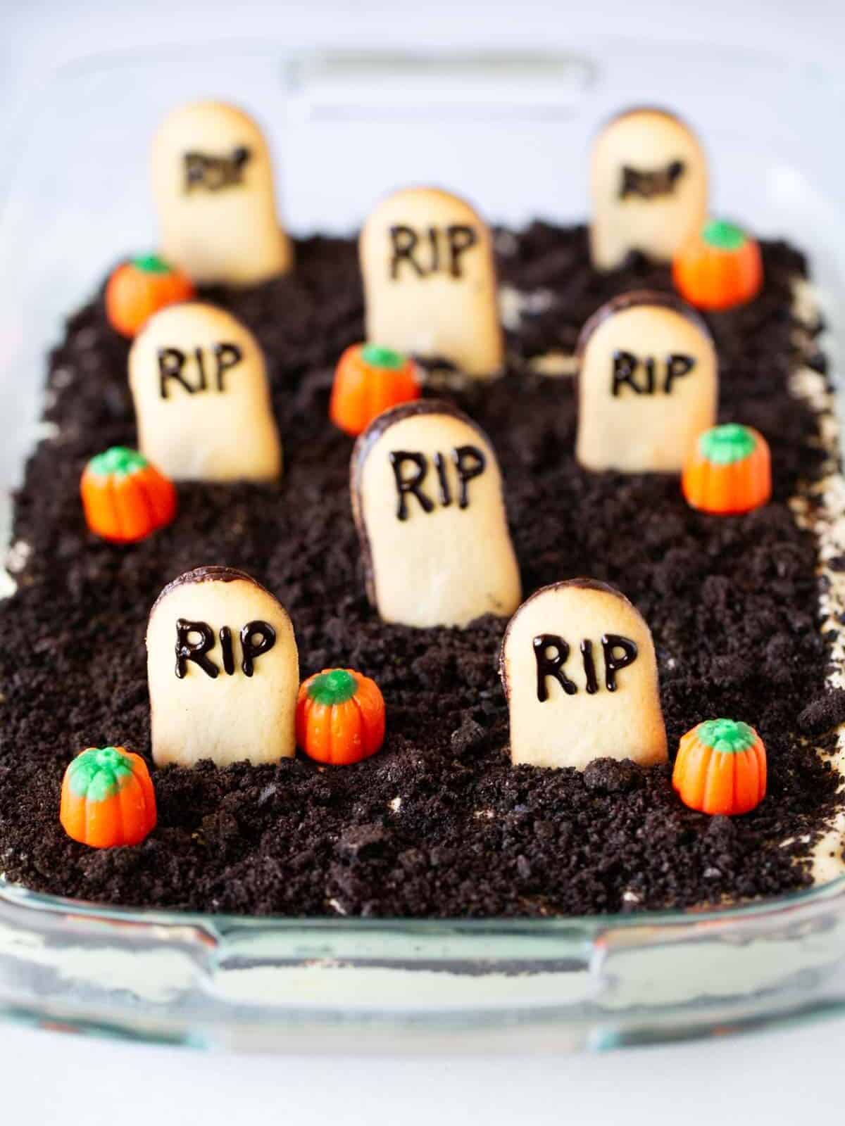 Oreo dirt cake in a glass dish with cookies and pumpkins on top.