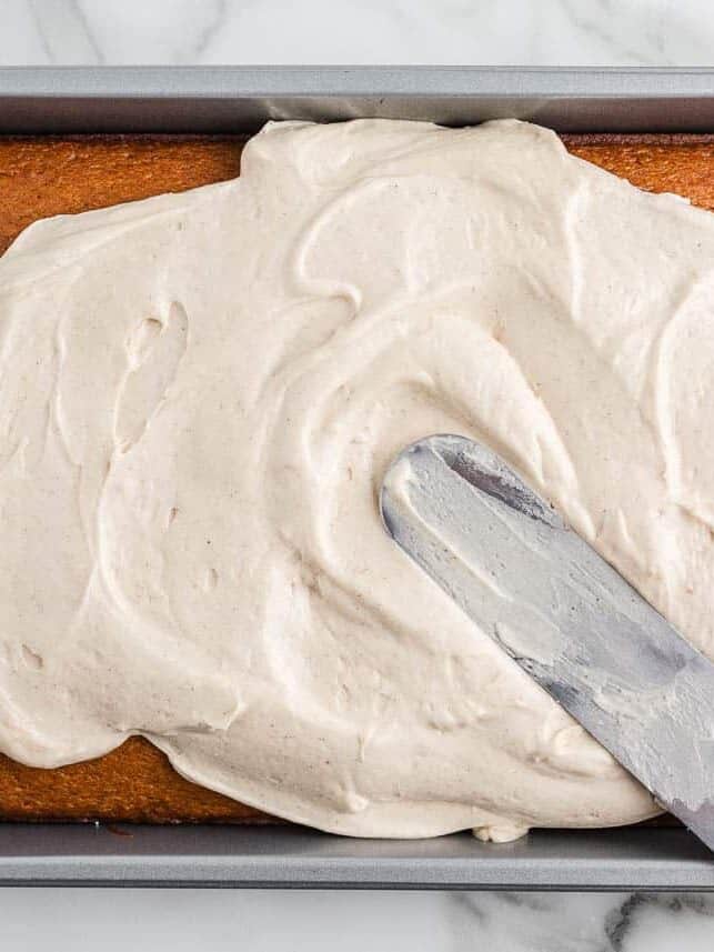 Spreading frosting onto pumpkin cake.