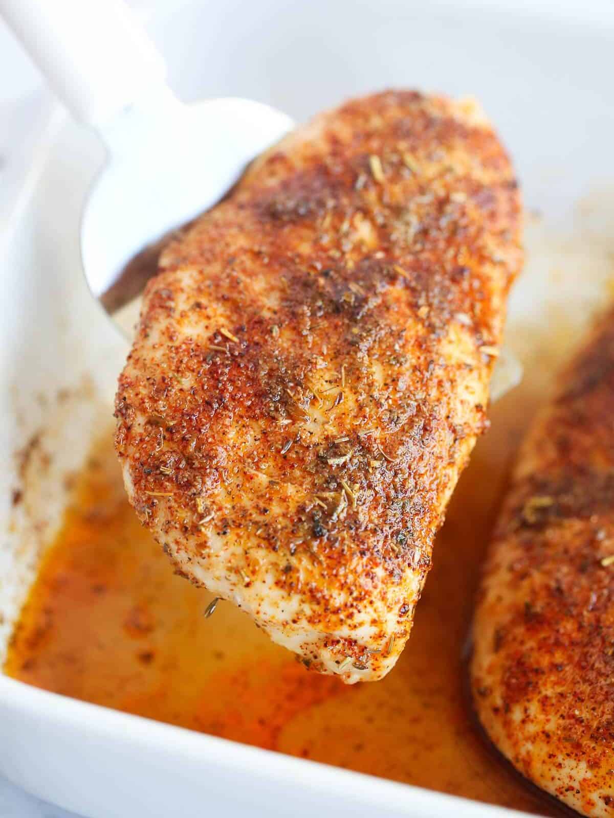 A spatula lifting the chicken breast out of the pan.