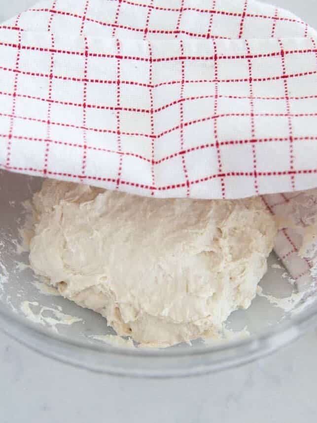 Covering easy homemade artsian bread dough with a towel.
