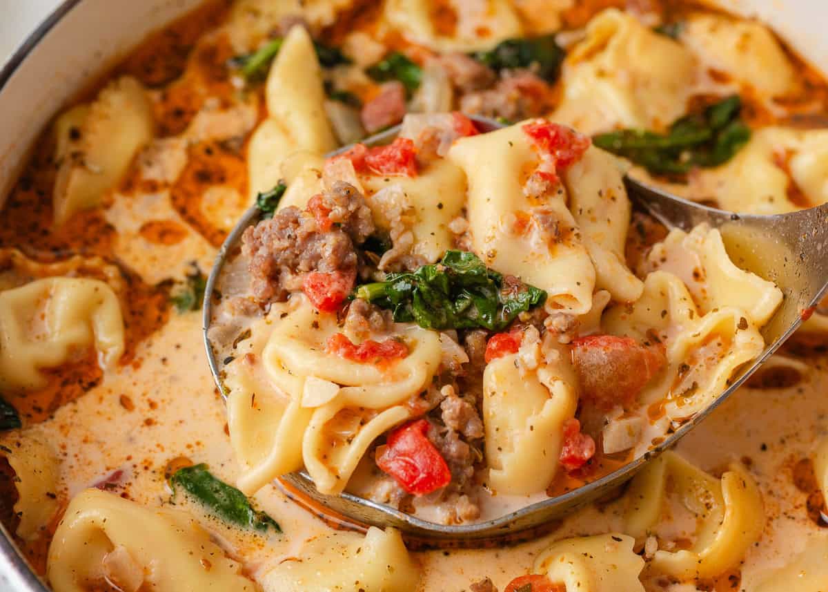Close-up of creamy Tuscan tortellini soup with cheese tortellini, Italian sausage, spinach and tomatoes.