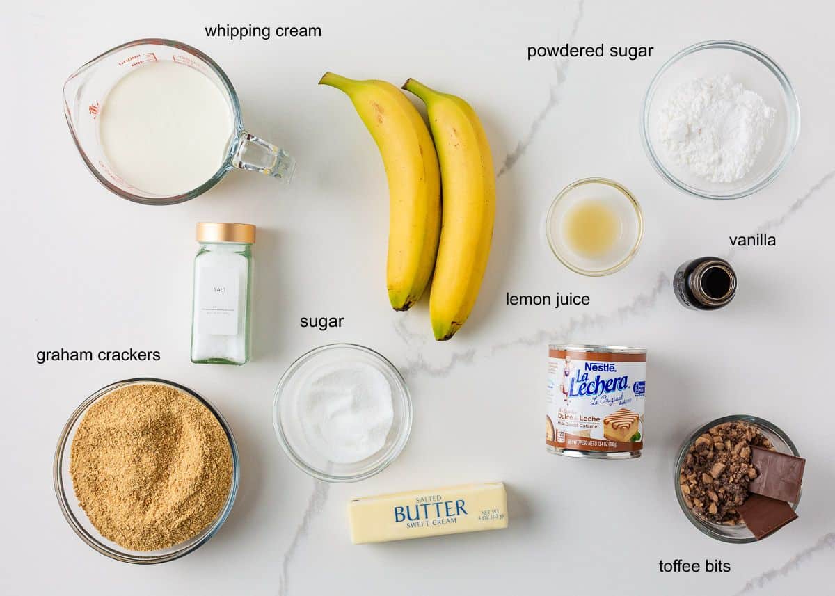 Banoffee pie ingredients including bananas, graham crackers, dulce de leche, whipping cream and toffee bits.