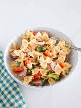 Overhead view of creamy Boursin cheese pasta with sausage, broccoli and tomatoes in a glass baking dish.