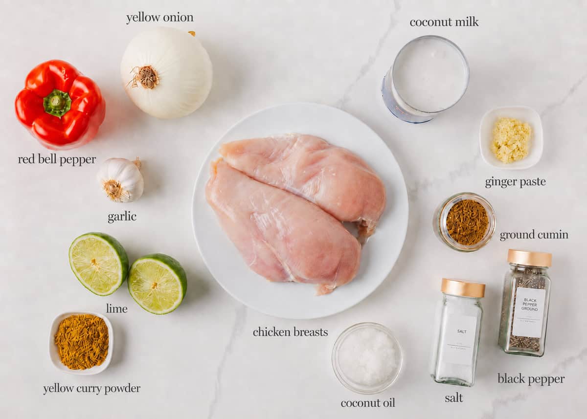 Ingredients for coconut curry chicken including chicken breast, coconut milk, red bell pepper, onion, garlic, ginger, lime and spices.