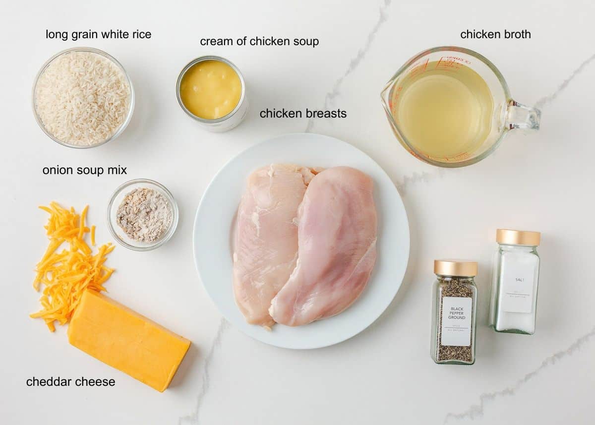 Ingredients for chicken and rice casserole, including chicken breasts, white rice, cream of chicken soup, chicken broth, onion soup mix, cheddar, salt and pepper.