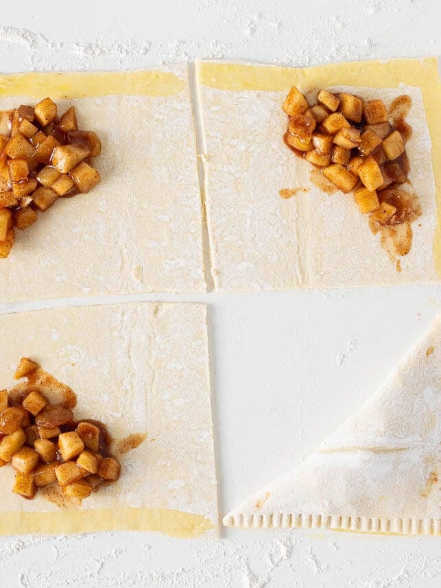 Puff pastry squares filled with cinnamon apple filling and folded into homemade apple turnovers.