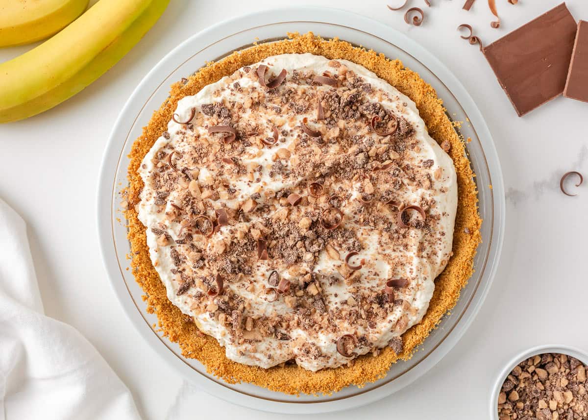 Finished banoffee pie topped with whipped cream, toffee bits and chocolate curls.