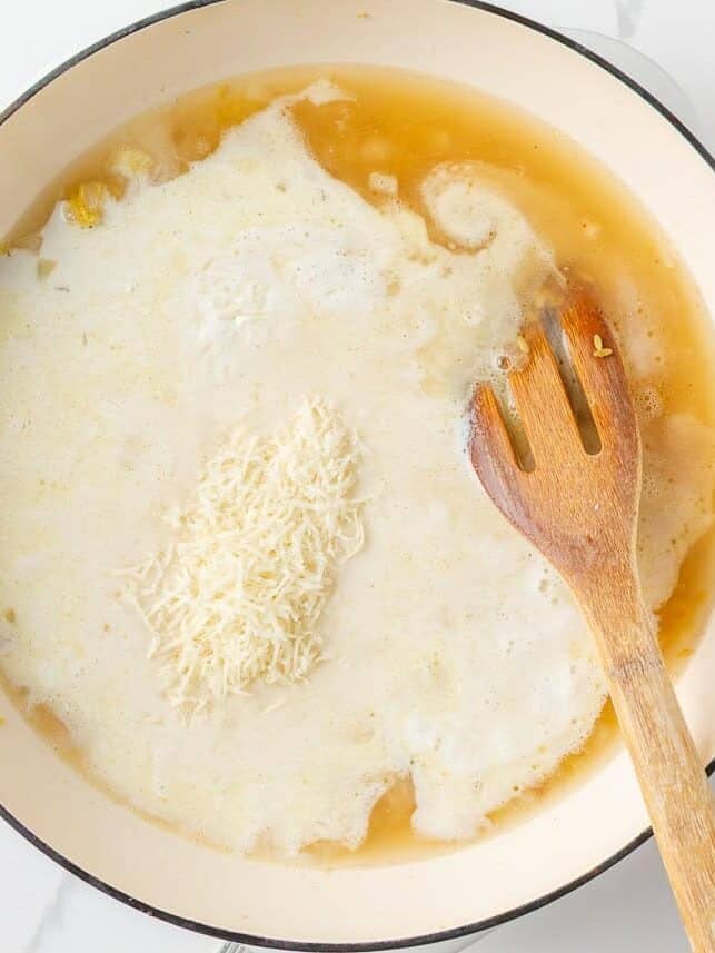 Cream, chicken broth and Parmesan added to toasted orzo in a skillet.